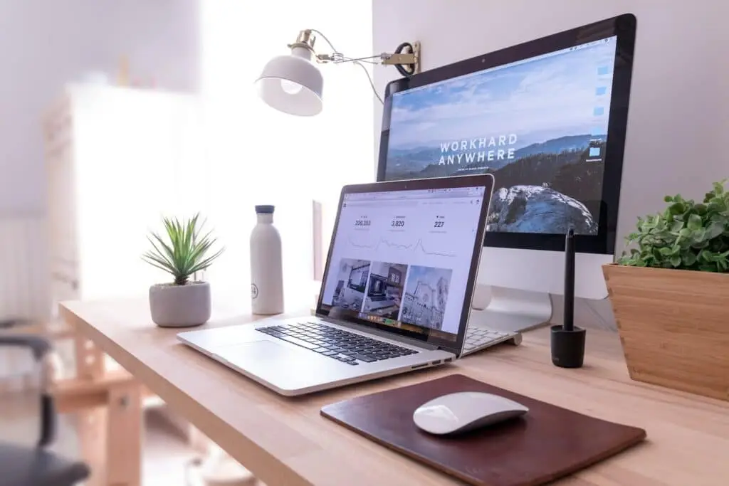 MacBook Pro sur une table à côté d'un iMac blanc et d'une souris magique